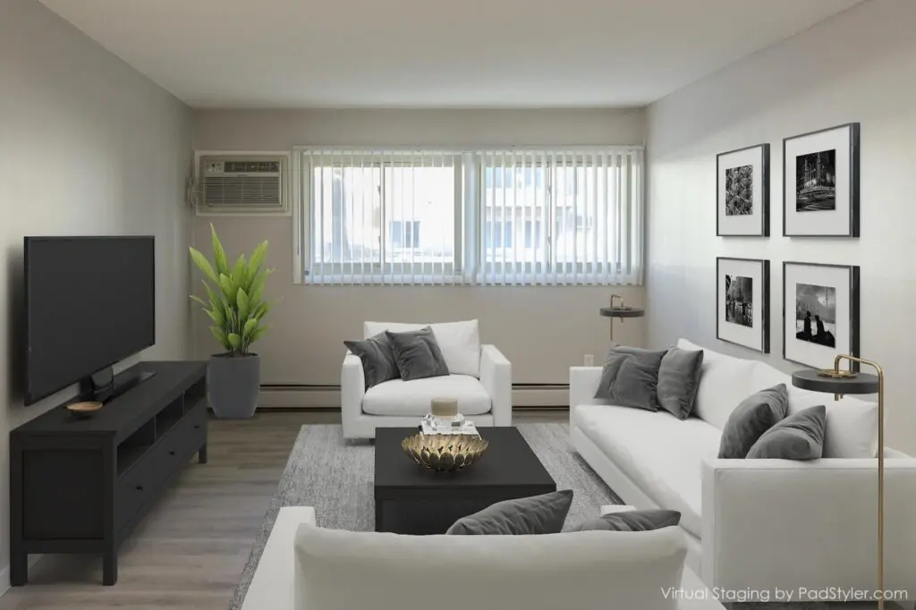 A modern living room with two white sofas, a black coffee table, a TV on a black stand, a potted plant, and framed wall art, featuring large windows with vertical blinds.