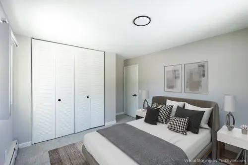 Modern bedroom with a double bed, gray and white bedding, two nightstands, framed wall art, a white closet, and neutral decor. Natural light comes in through a window on the left.