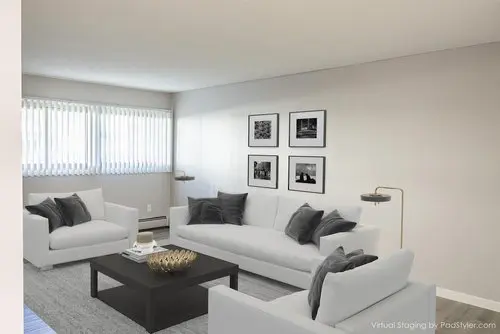 A modern living room with white sofas, a black coffee table, gray cushions, wall art, and vertical blinds on the windows.