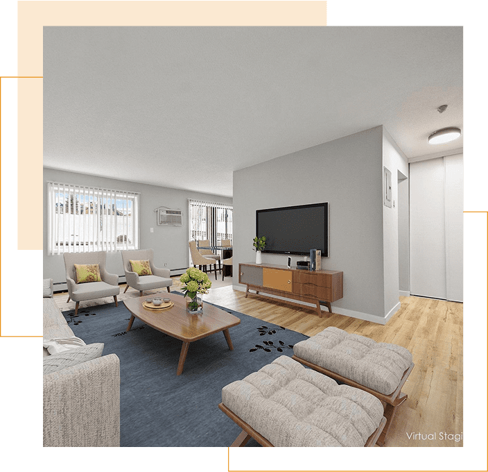 A modern living room with light-colored furniture, a wall-mounted TV, wooden flooring, large windows with blinds, and a coffee table with flowers.