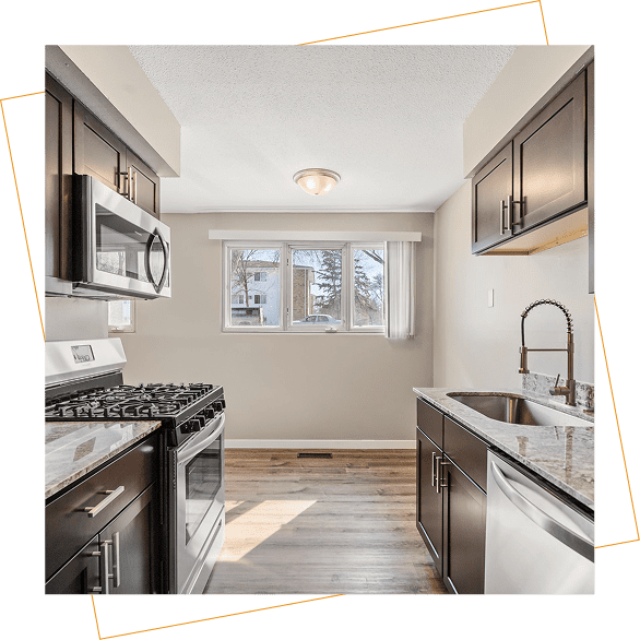 Modern kitchen with stainless steel appliances, dark cabinets, granite countertops, and a window letting in natural light.