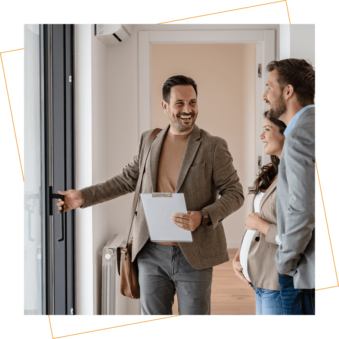 A real estate agent opens a door and shows a house to a smiling couple standing together in a bright, modern interior.