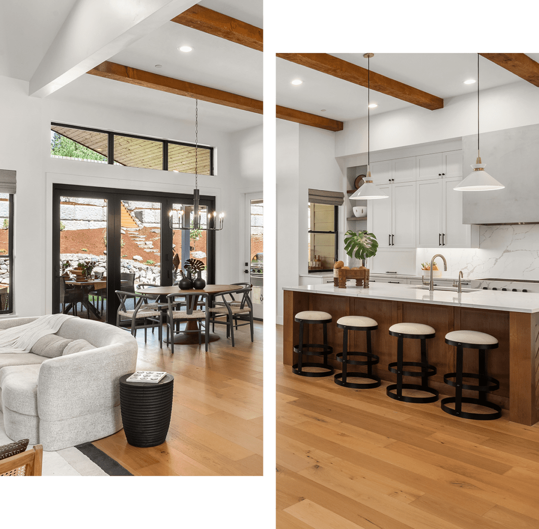 Open-concept living space with a modern kitchen, white cabinetry, an island with stools, and a dining area near large windows and sliding doors.